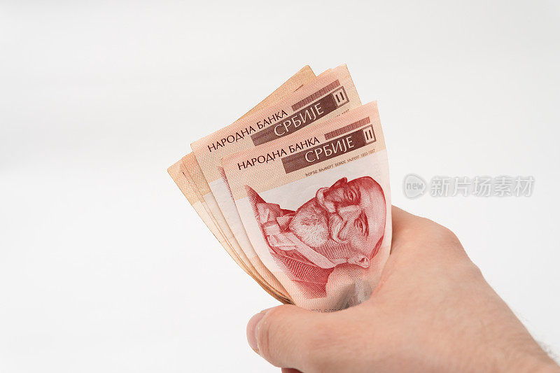 一名男子拿着一堆钱，1000 RSD塞尔维亚第纳尔纸币被隔离在白色背景上